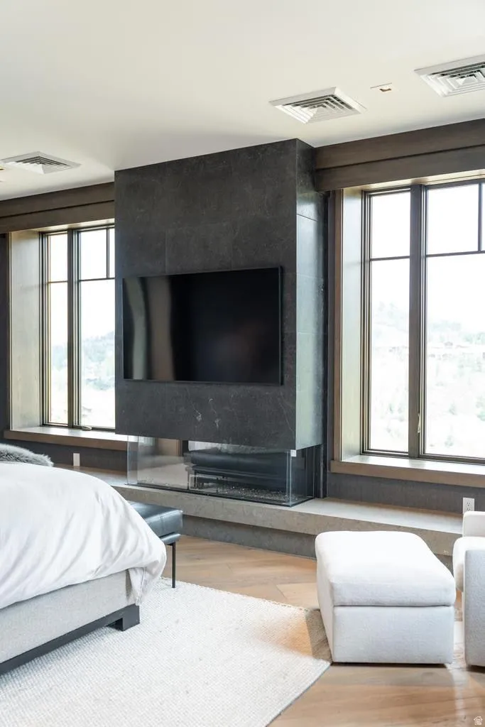 Modern fireplace feature with a glass-enclosed firebox, integrated television, and dark stone surround