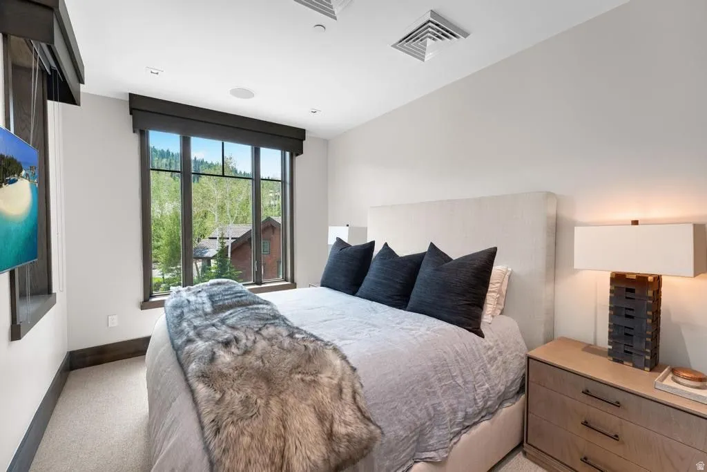 Large multi-pane window with dark trim, recessed ceiling lighting, wall-mounted television, built-in ceiling speaker, and light-toned carpeting