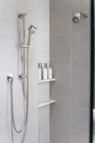 Shower with a handheld spray unit, a fixed shower head, and a recessed shelving niche