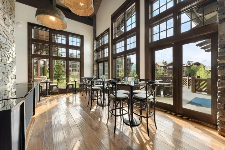 Spacious interior featuring expansive floor-to-ceiling windows with dark wood framing, rich wood-finish flooring, and a stone accent wall