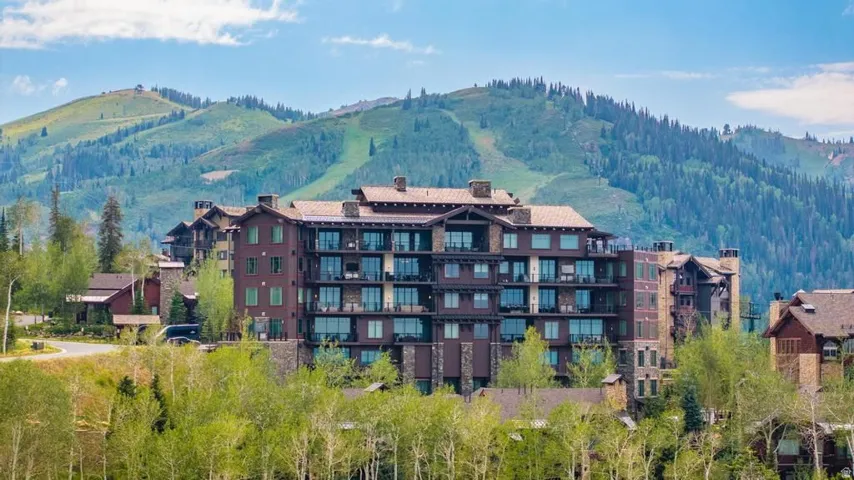 Multi-story residence featuring extensive balconies, a stone and wood facade, and a multi-gabled roofline