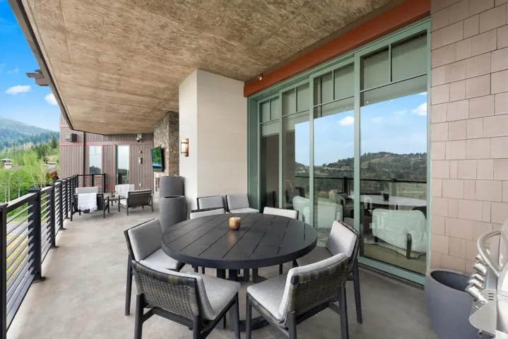 Expansive concrete patio featuring a mountain backdrop, black metal railings, and large sliding glass doors