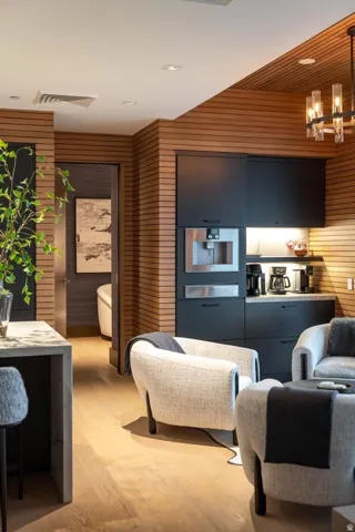 Integrated wet bar with black cabinetry, built-in coffee maker, and under-cabinet lighting