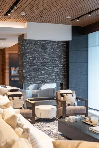 Modern living space featuring a floor-to-ceiling stone-faced fireplace with a glass barrier