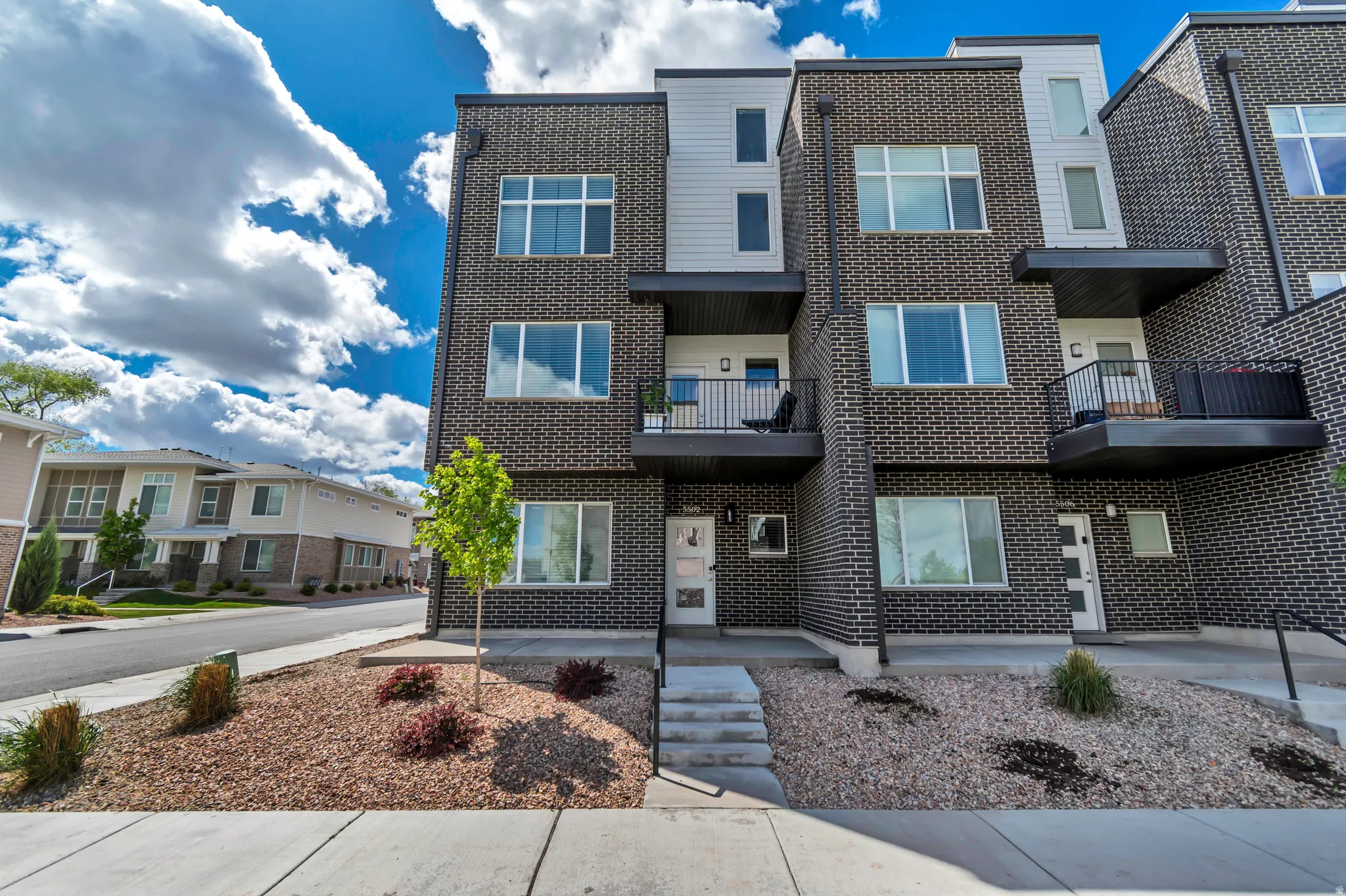Modern tri-level townhome featuring dark brick and light siding exterior