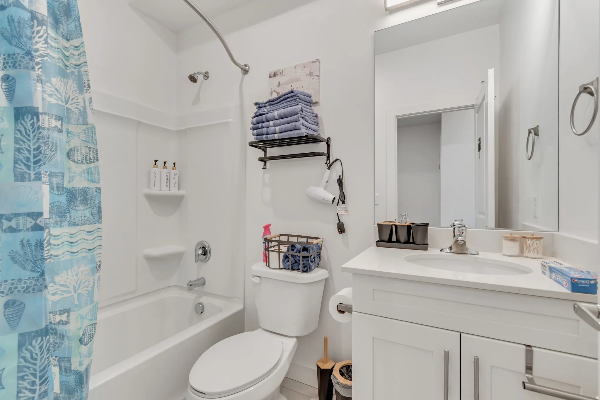 Bright bathroom featuring a white vanity with an undermount sink, a large wall-mounted mirror, and a chrome faucet