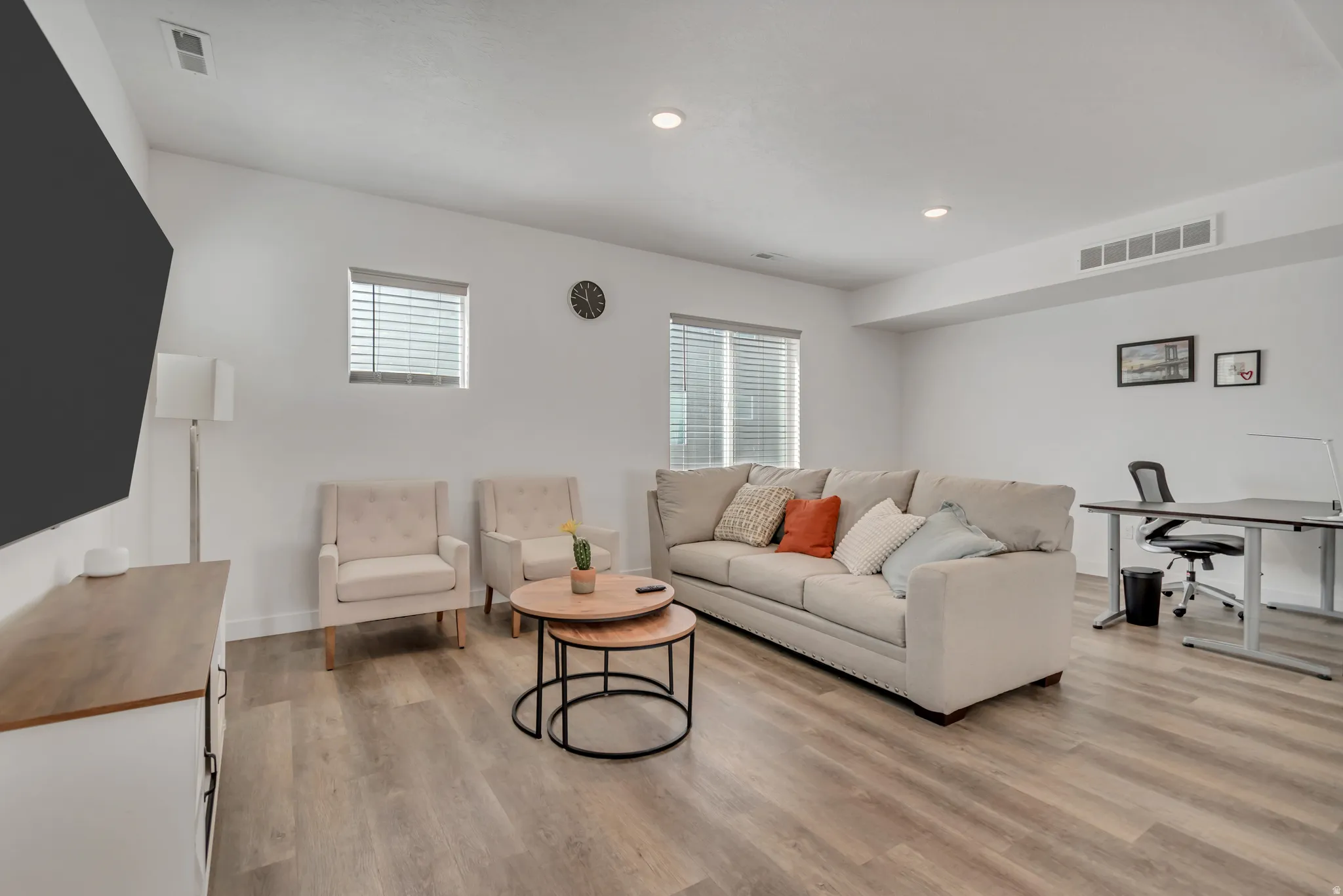 Open-concept living space featuring wood-finish flooring, recessed lighting, and multiple windows with blinds