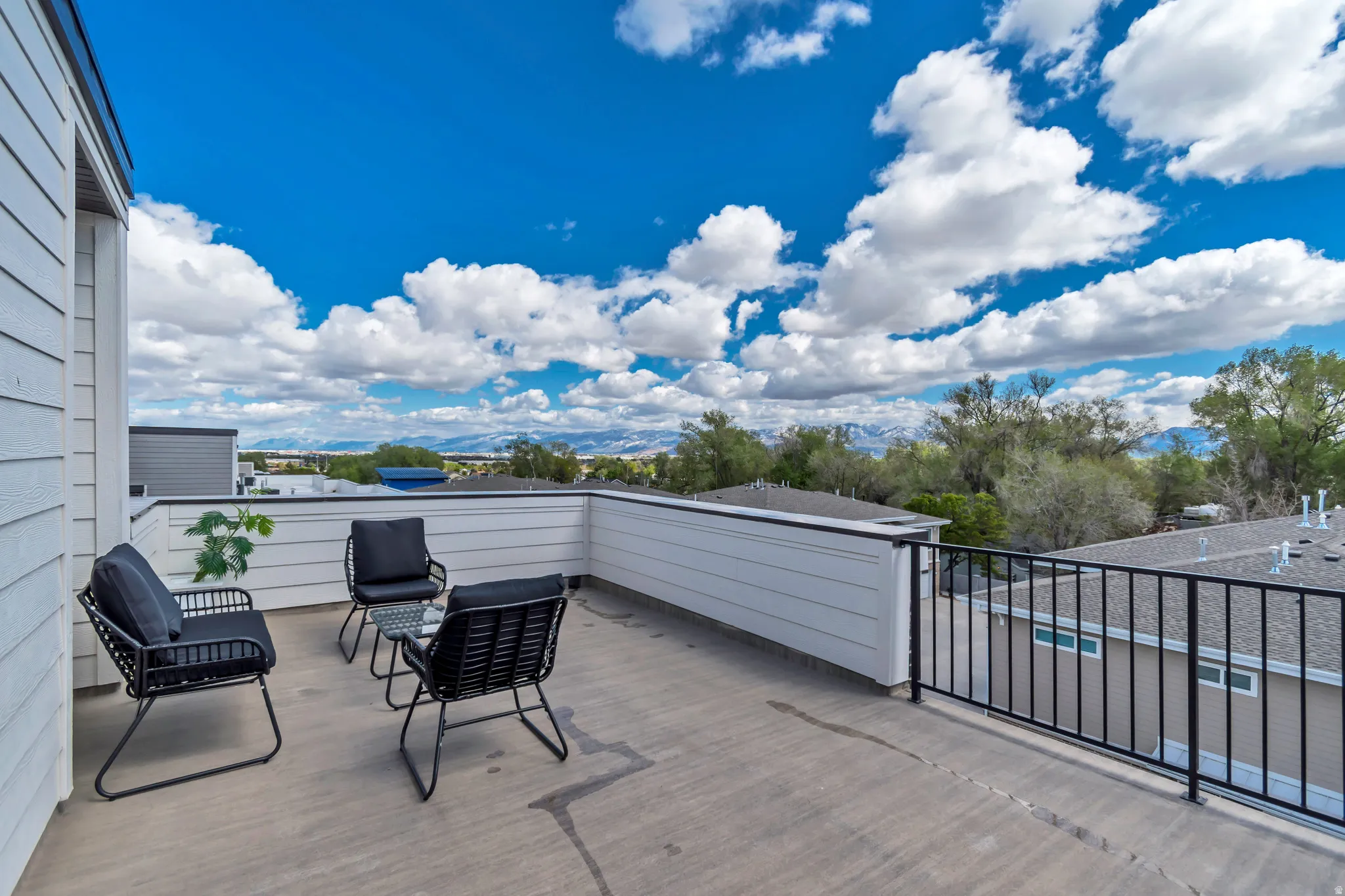 Rooftop deck featuring a concrete surface, white siding, and a black metal railing
