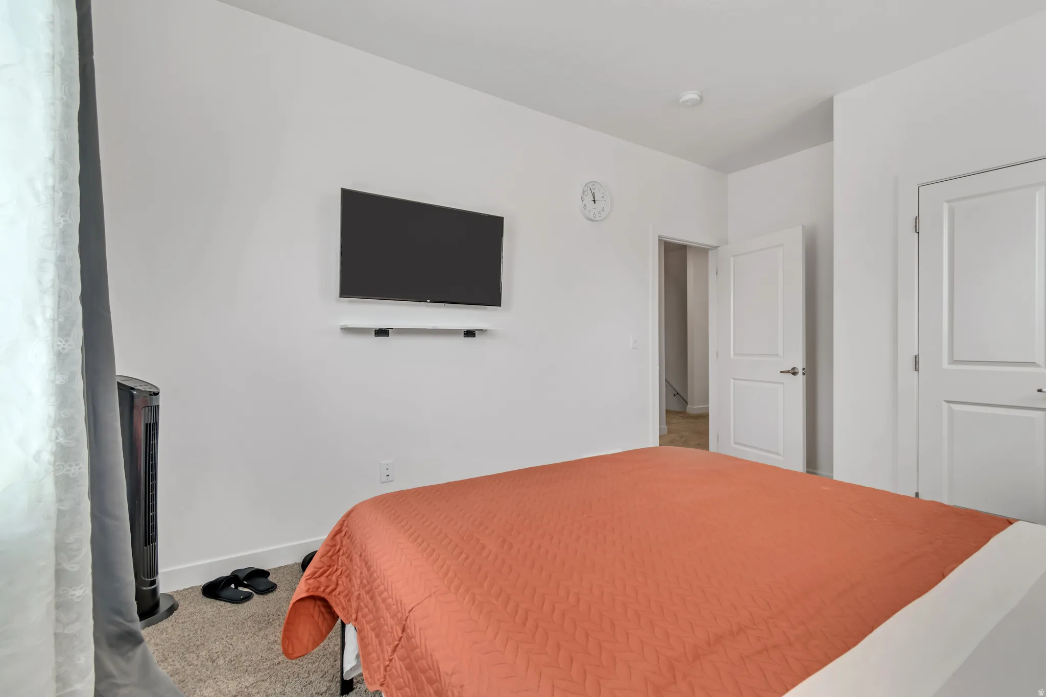 Bright interior room featuring a wall-mounted television, two white panel doors, and neutral carpet flooring