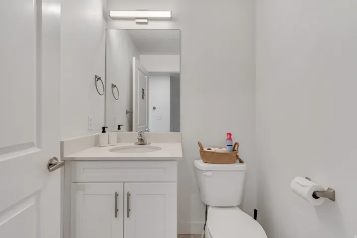 Powder room featuring a white single-sink vanity with a light-toned countertop, a rectangular mirror, and a wall-mounted light fixture
