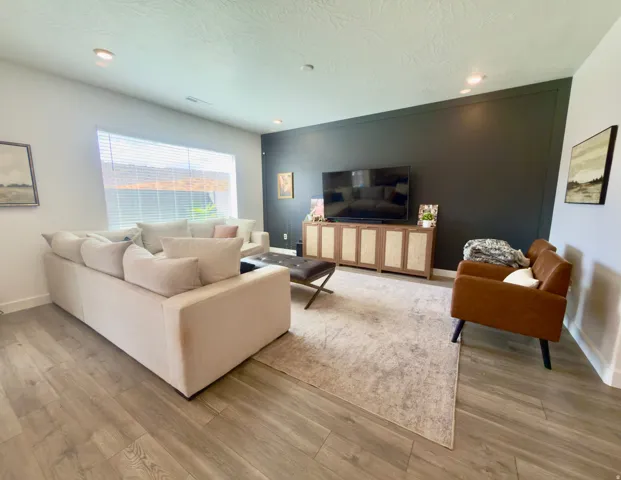Spacious living area featuring wood-finish flooring, recessed lighting, and a large picture window