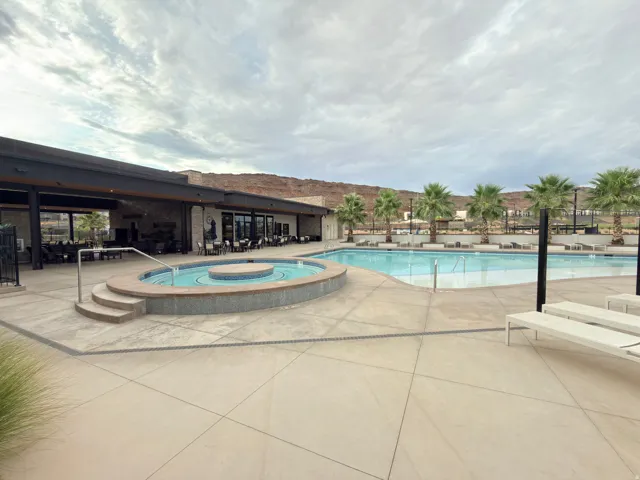 Resort-style pool area featuring a large swimming pool, integrated spa with decorative tiling, and surrounding concrete patio