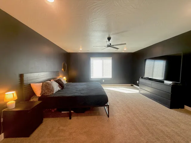 Carpeted room featuring a ceiling fan, recessed lighting, and a window with horizontal blinds