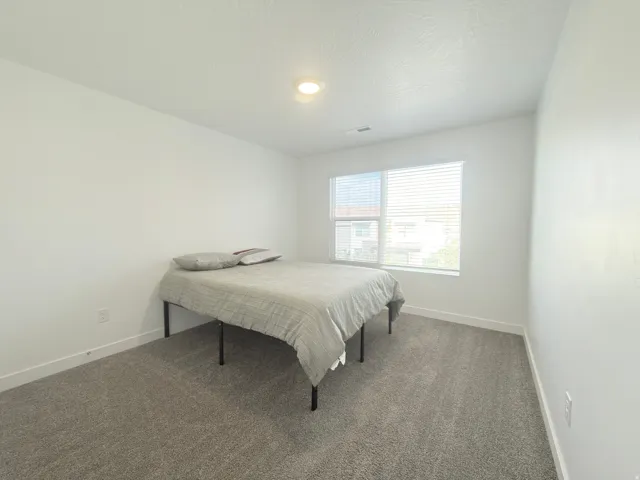 Carpeted room featuring a large window with blinds, white walls, and a recessed ceiling light