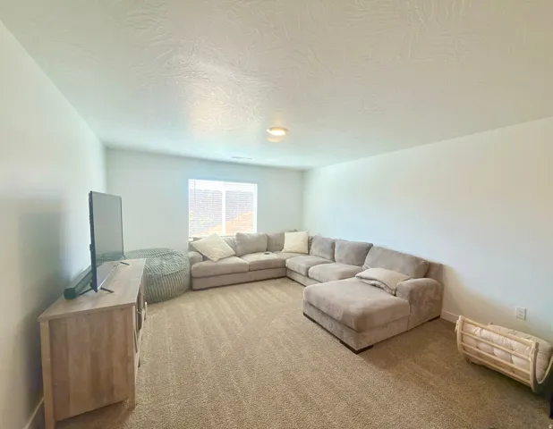 Spacious room featuring neutral carpeting, light-colored walls, and a window with blinds