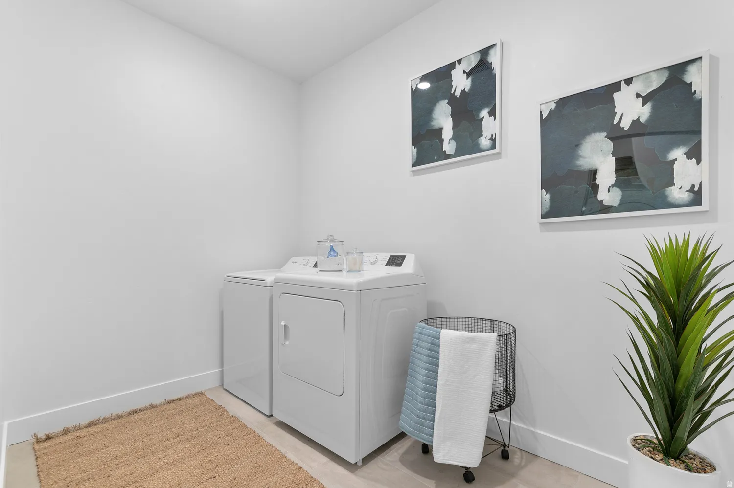 Dedicated laundry area featuring light-toned flooring and white baseboards