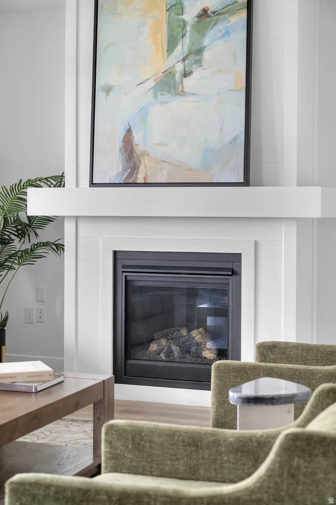 Contemporary fireplace with a black metal insert and glass screen, framed by a white mantel and shiplap-style surround