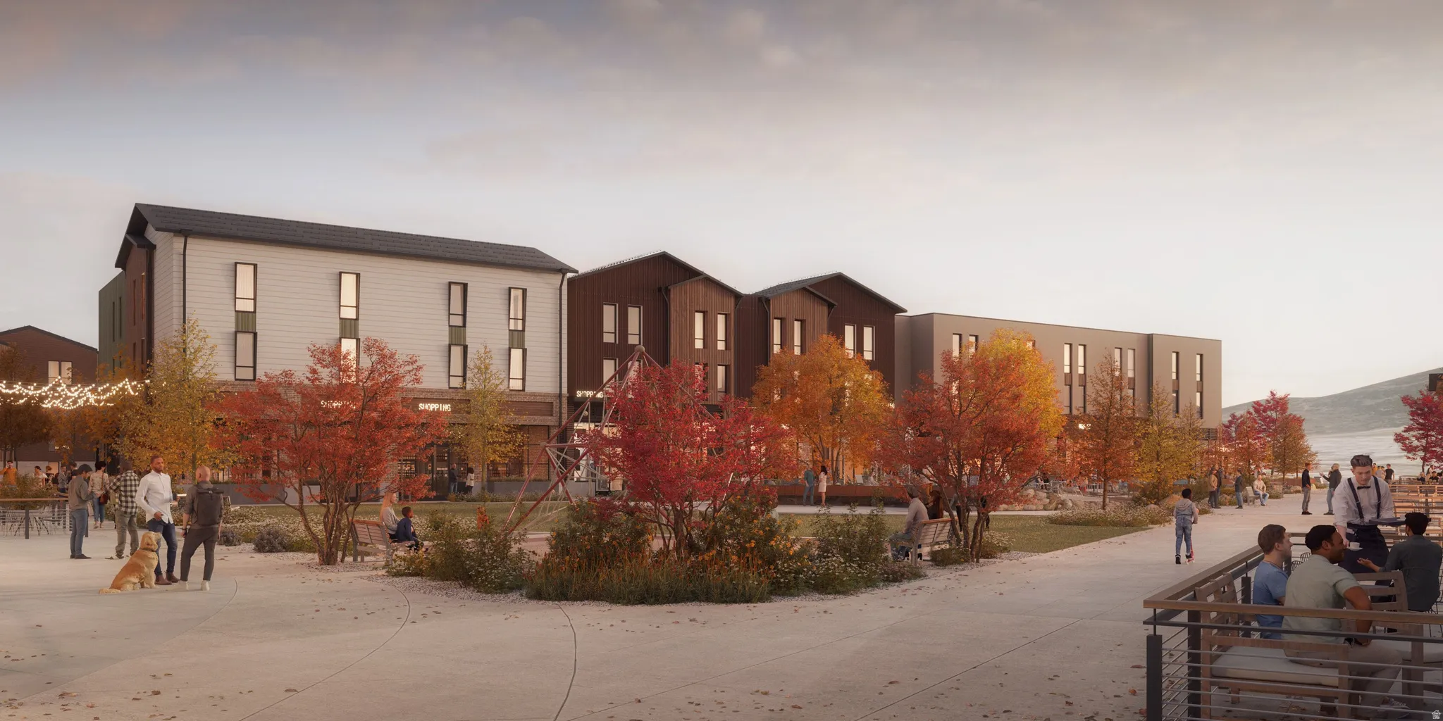 Modern mixed-use development featuring multi-story buildings, extensive hardscaping, mature trees, outdoor seating areas, and a visible body of water