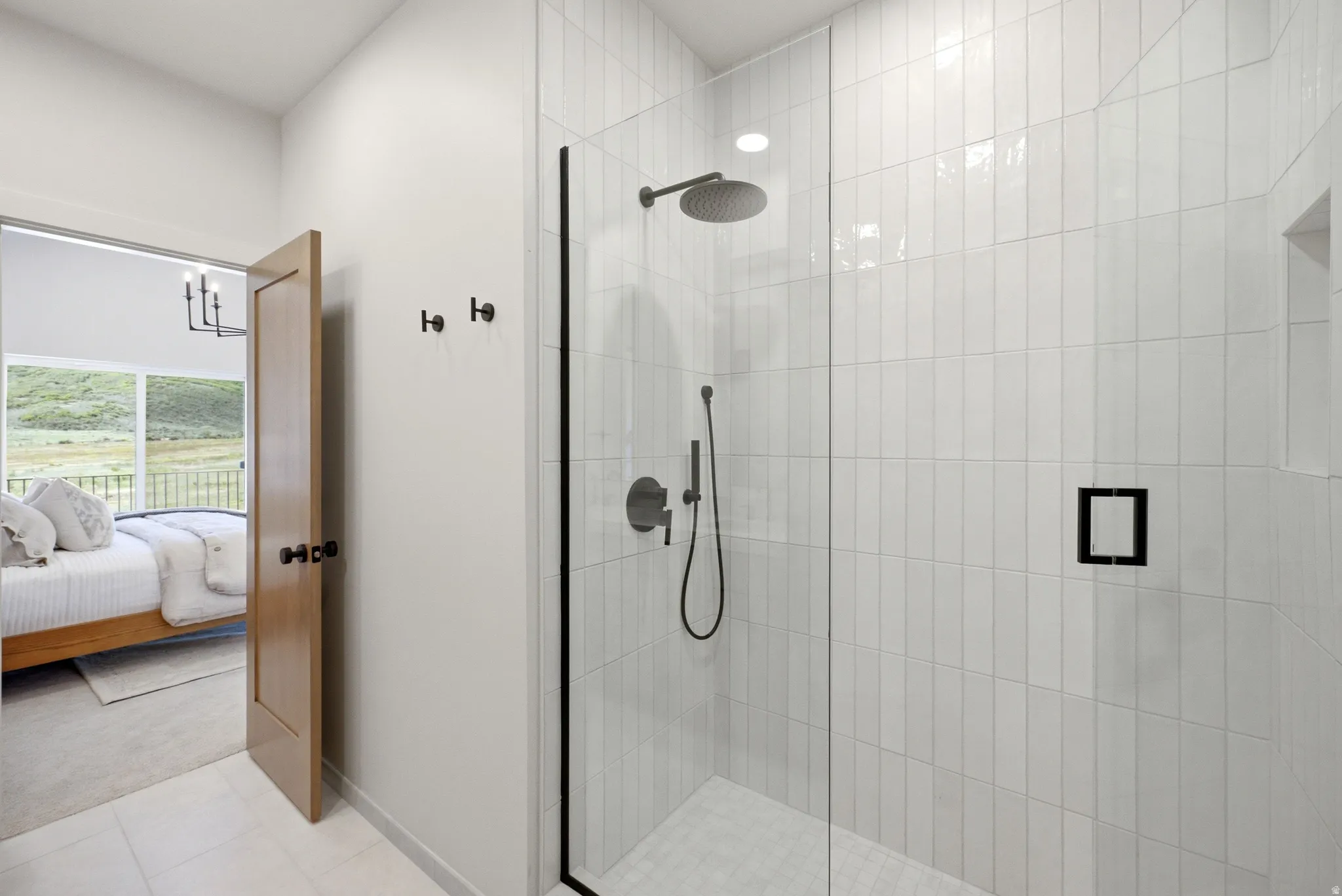 Glass-enclosed shower with vertical white tile, rain shower head, and built-in shower niche