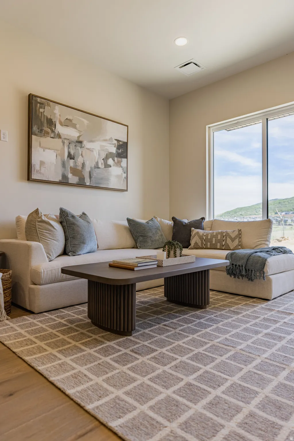 Spacious room featuring wood-finish flooring, a large area rug with a geometric pattern, and a sliding glass door