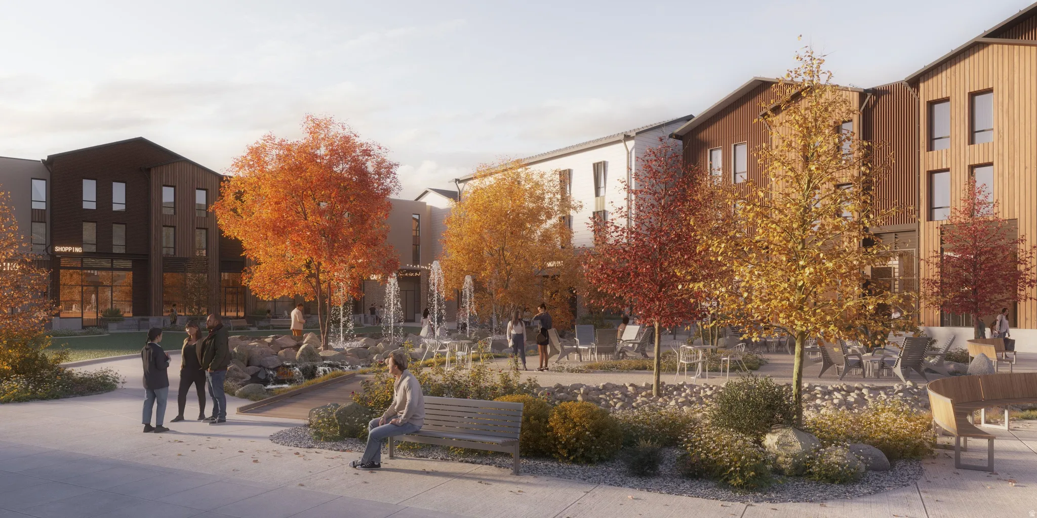 Expansive outdoor common area featuring multiple seating arrangements, mature autumn trees, a central rock garden with water features, and modern building facades with varied materials