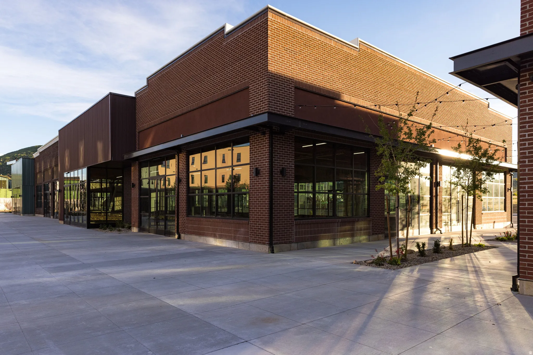 Brick commercial building featuring extensive storefront windows and a large concrete patio