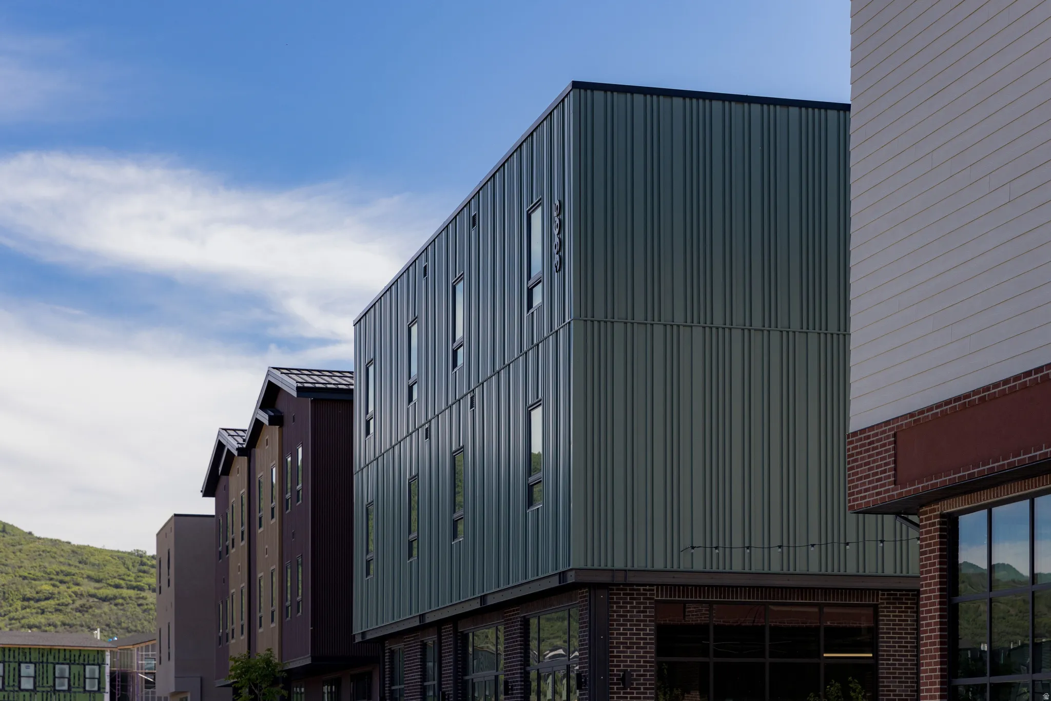 Modern facade featuring vertical panel siding and a brick-clad lower level