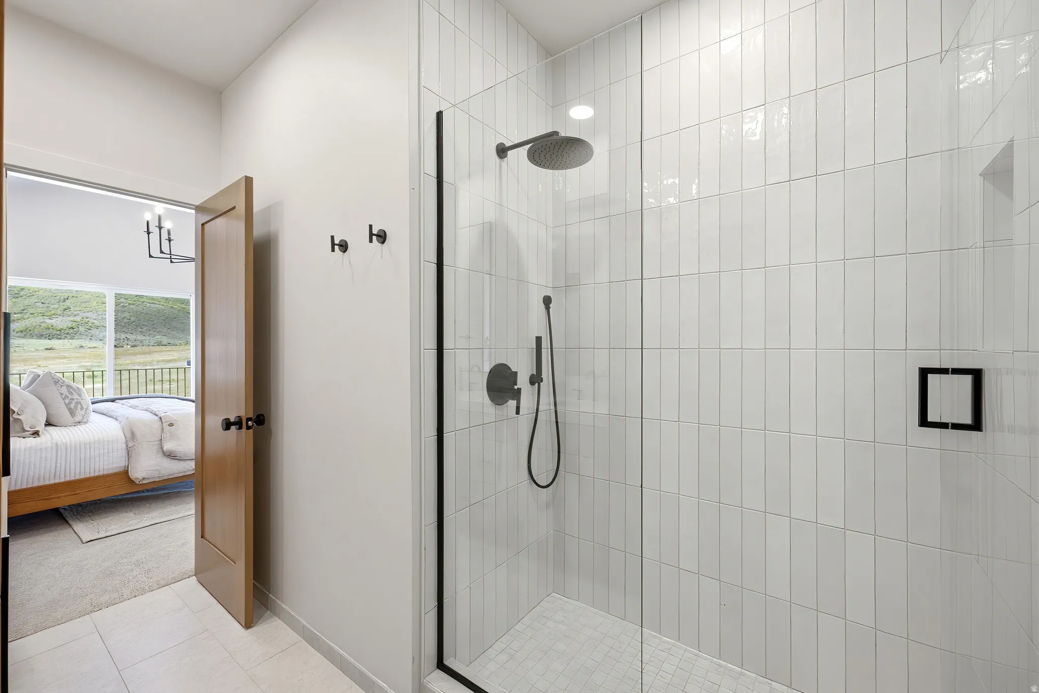 Walk-in shower featuring vertical subway tile, matte black fixtures, and a glass enclosure