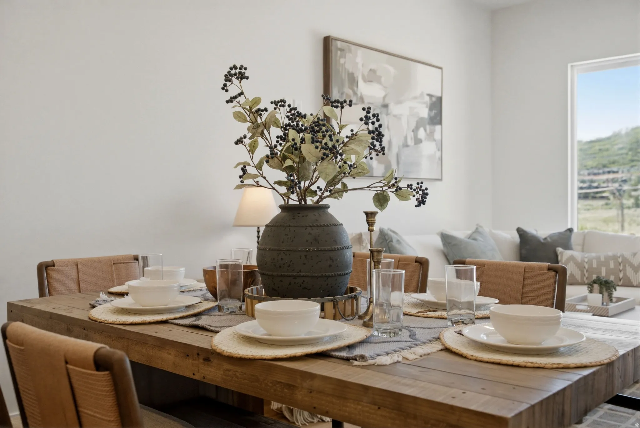 Open-concept dining area featuring a rectangular wood dining table, woven-back dining chairs, and a large picture window