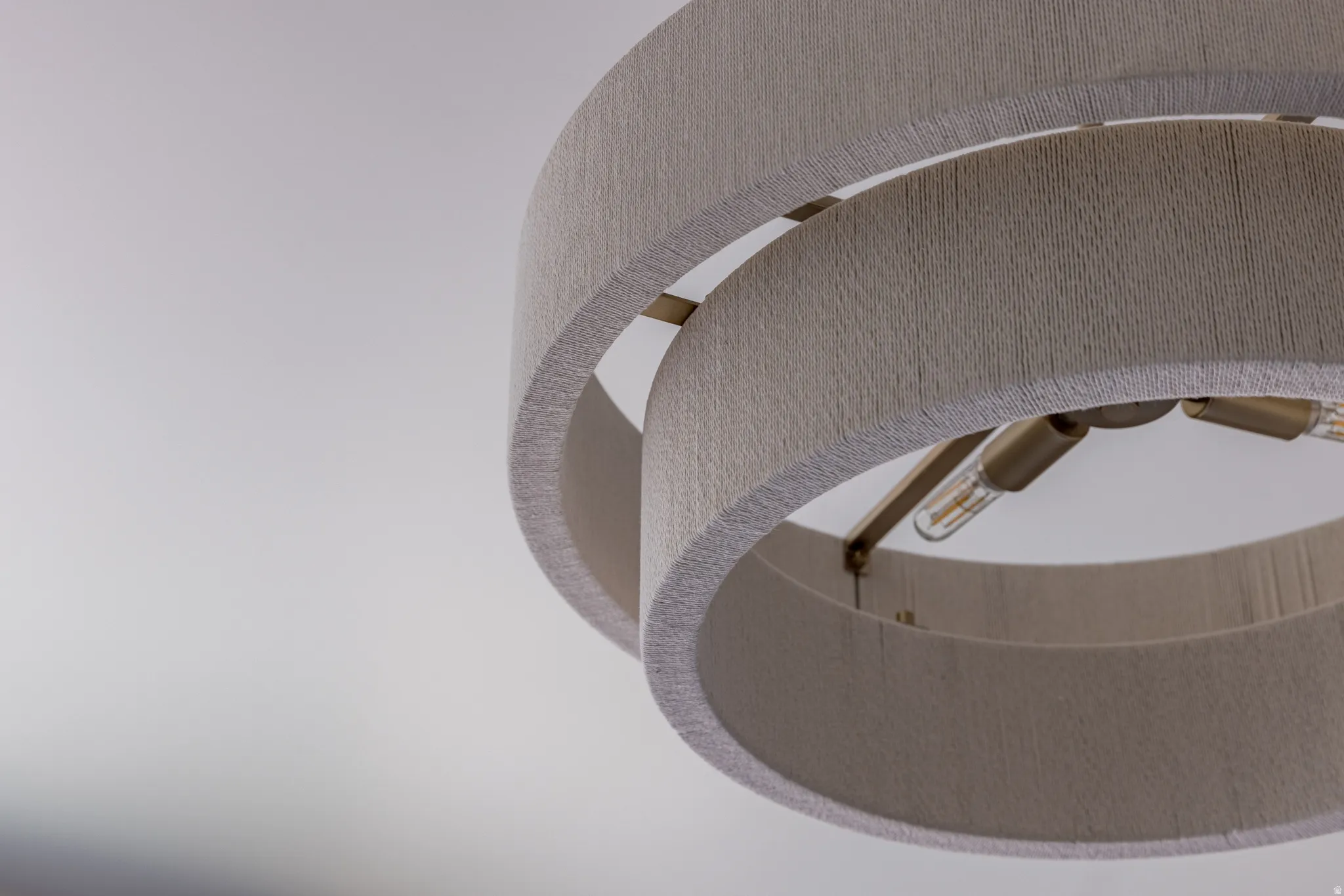 Contemporary ceiling light fixture featuring dual fabric-wrapped drum shades, exposed Edison-style bulbs, and a muted metal frame