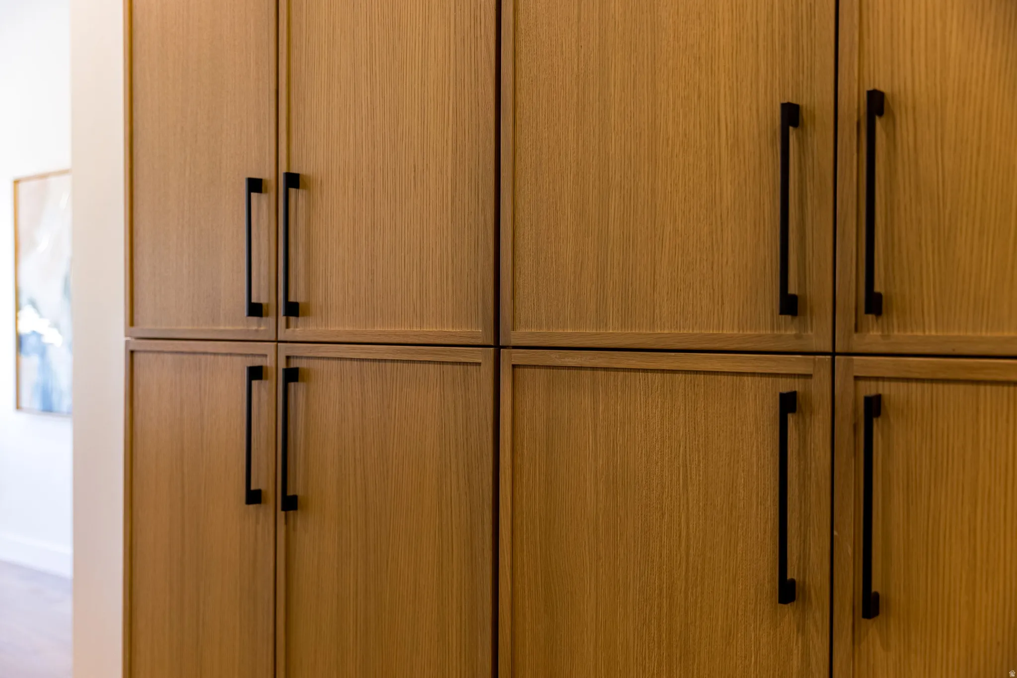 Custom built-in cabinetry with a light wood-finish and matte black hardware