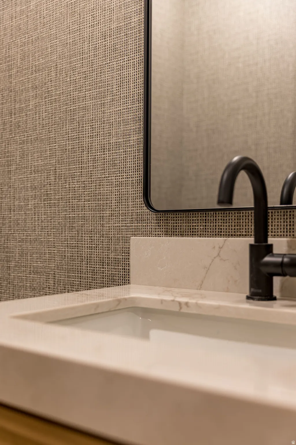 Integrated rectangular sink with a light-toned countertop, matte black faucet, and a black-framed mirror