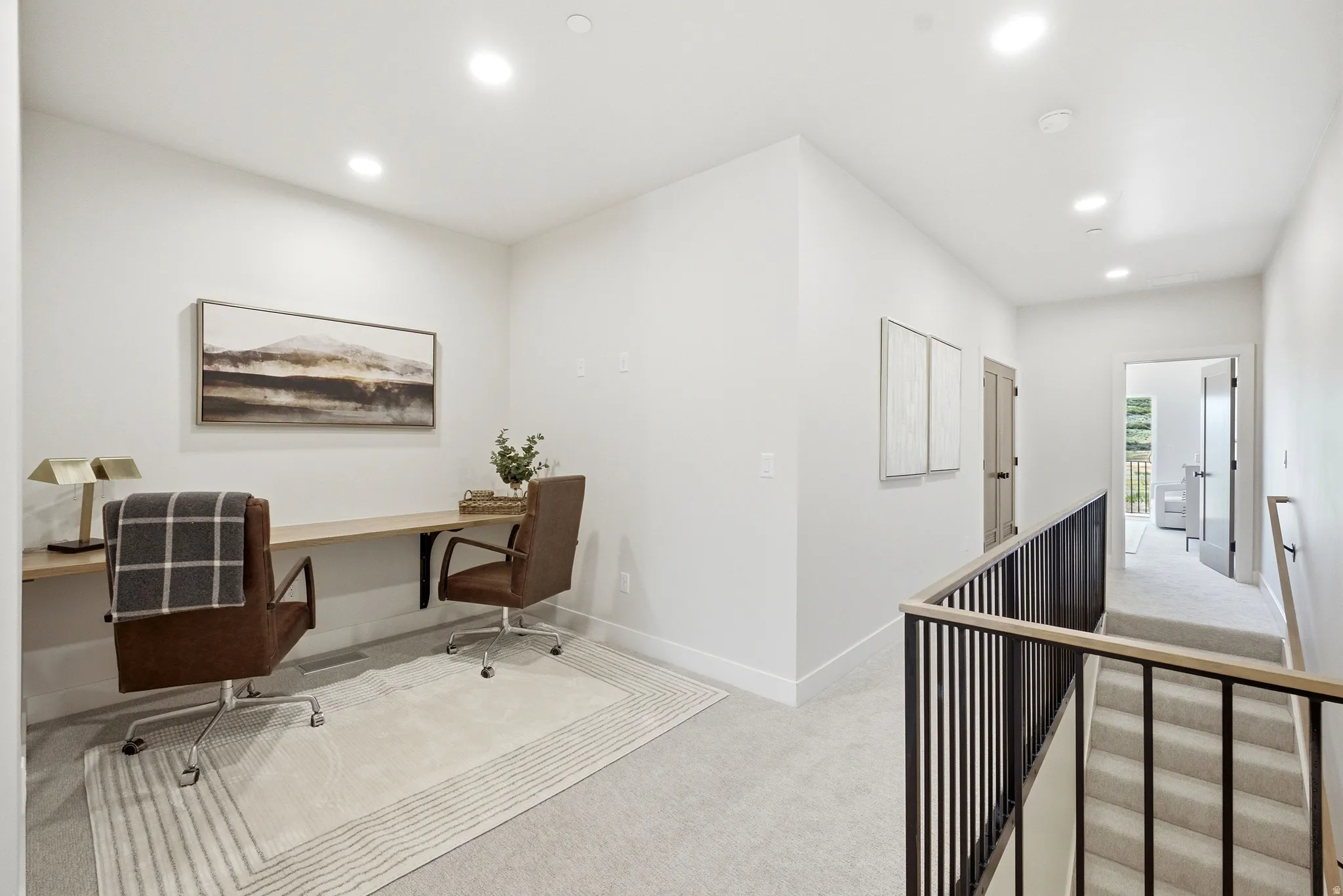 Upper-level landing featuring a built-in wood-finish desk, recessed lighting, and carpeted flooring