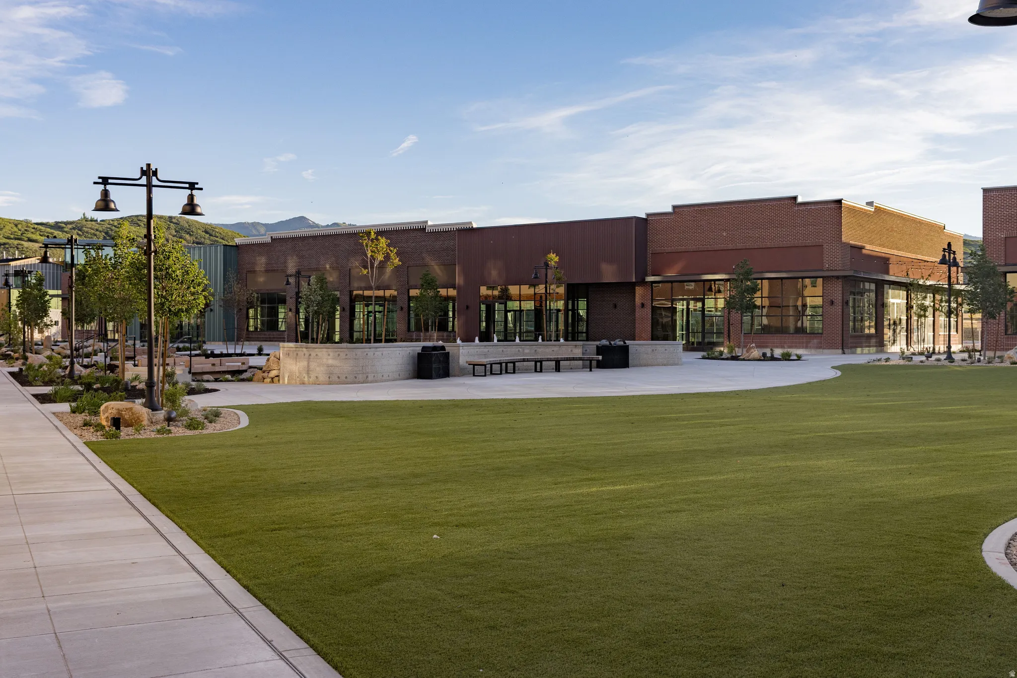 Expansive green lawn with surrounding concrete pathways and contemporary street lighting