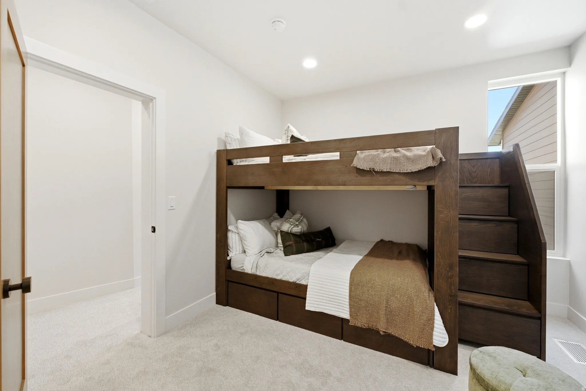 Built-in bunk bed with integrated storage drawers and a staircase entry