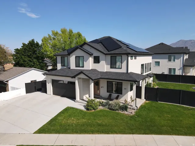 Modern two-story stucco exterior featuring a dark asphalt shingle roof and black-framed windows