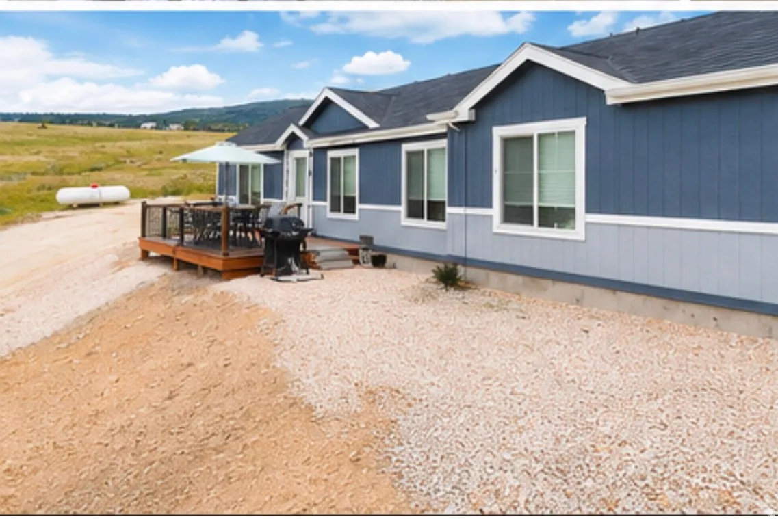 Exterior featuring a dark blue and light blue two-tone siding, white trim windows, an elevated wood deck with black railings, and a gravel ground cover