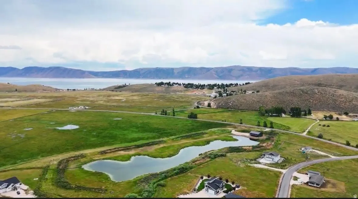 Expansive landscape featuring a large body of water, rolling hills, and multiple residential properties