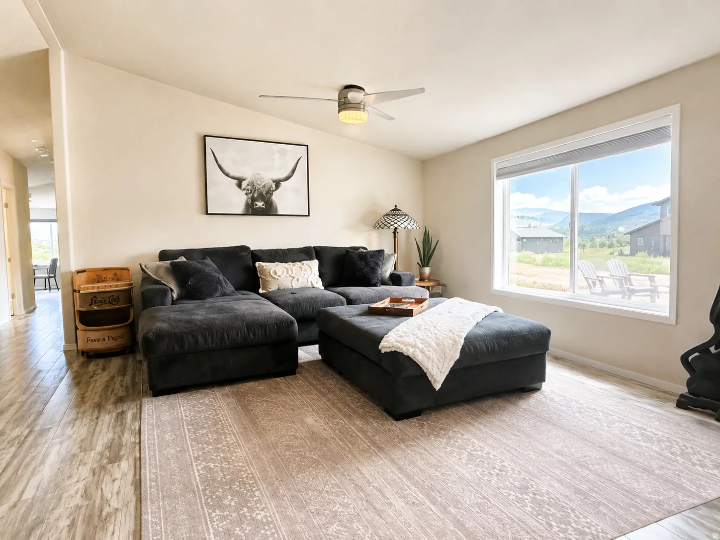 Living area featuring wood-finish flooring, a contemporary ceiling fan, and a large picture window