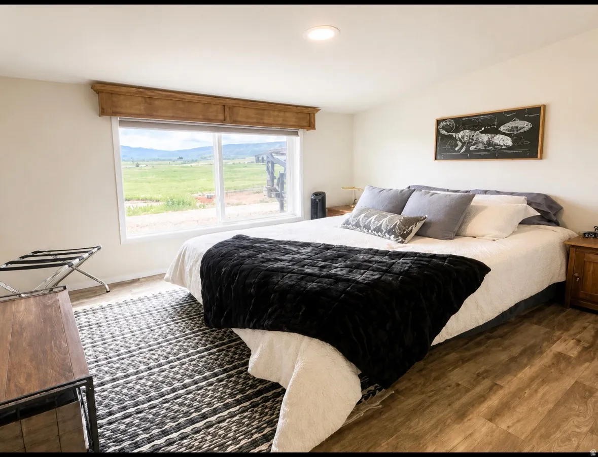 Bedroom featuring wood-finish flooring, a rectangular window with a wooden valance, and a recessed ceiling light