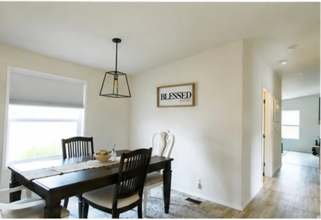 Dining area featuring a modern black geometric pendant light fixture and a large window with roller shades