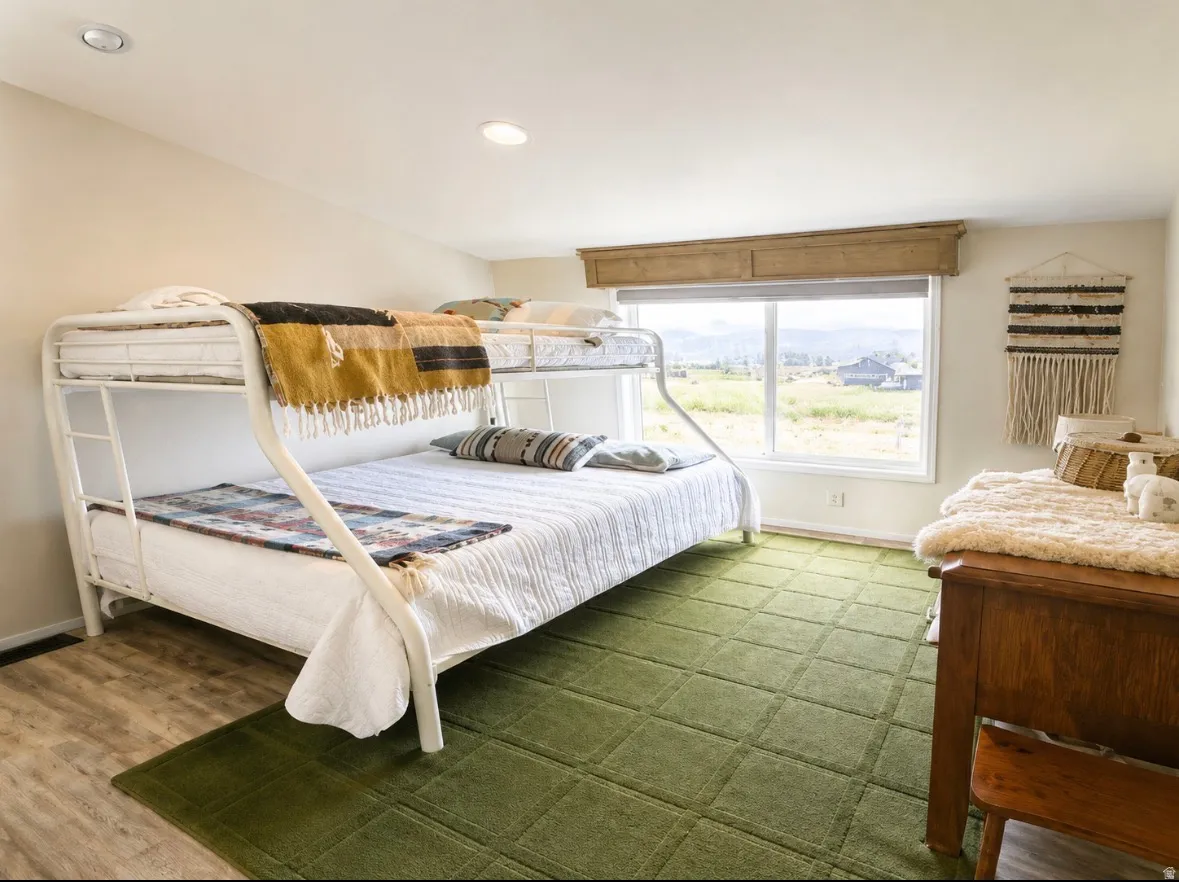 Spacious room featuring wood-finish flooring, recessed lighting, and a large window