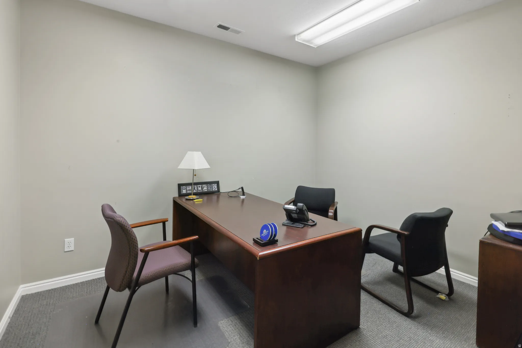 Private office space featuring neutral wall paint, white baseboards, and grey carpet flooring