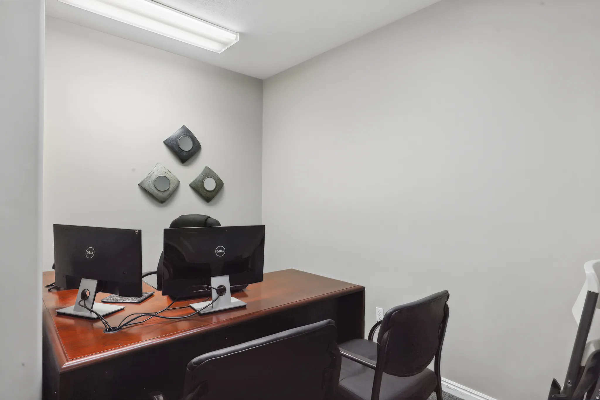 Dedicated workspace featuring light gray walls, white baseboards, and overhead fluorescent lighting