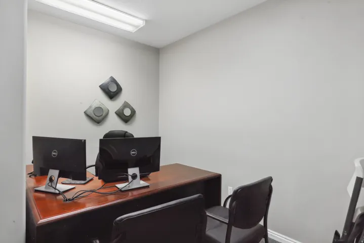 Dedicated workspace featuring light gray walls, white baseboards, and overhead fluorescent lighting