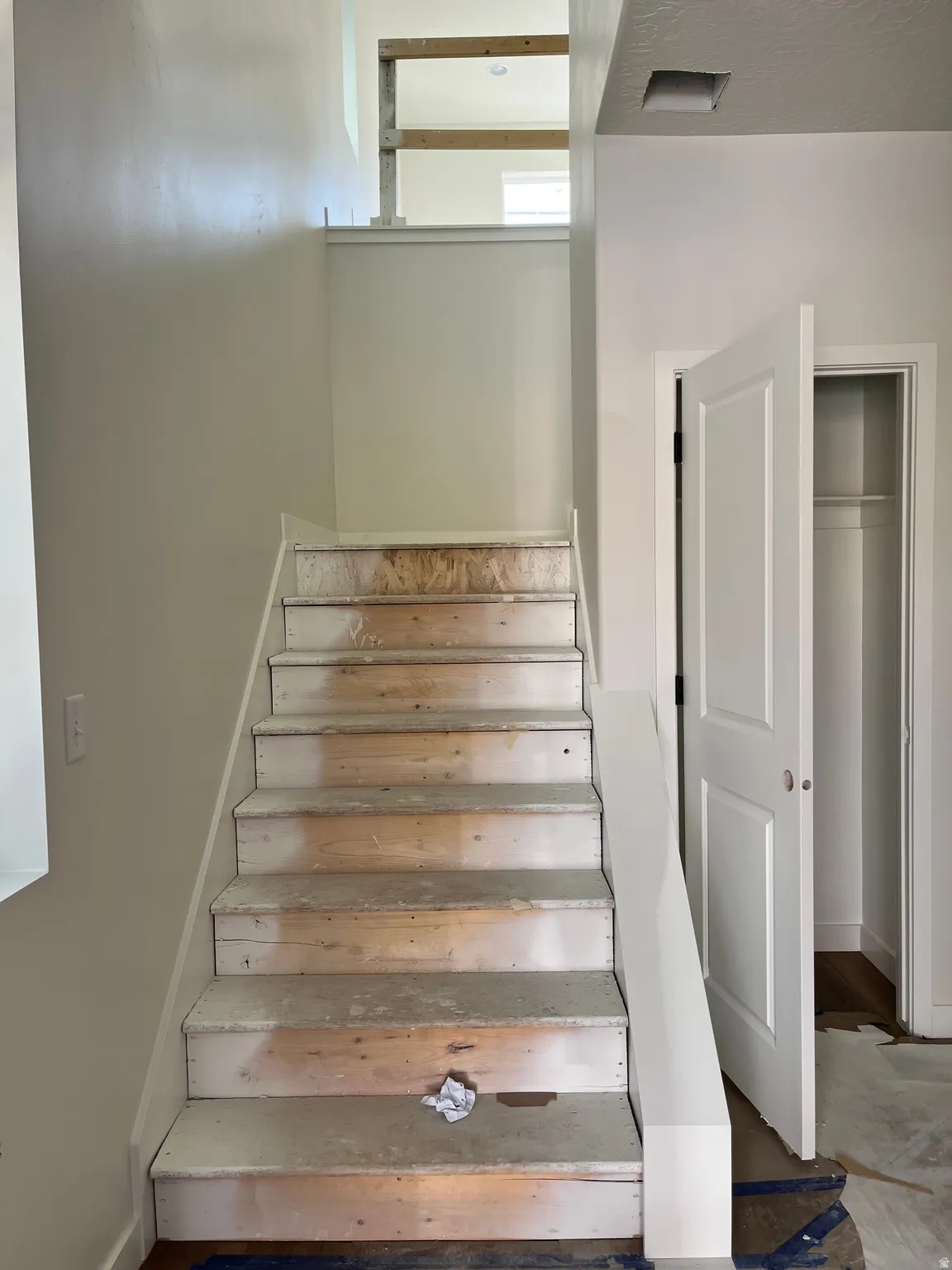 Staircase with unfinished wood treads, white risers, and white painted stringer