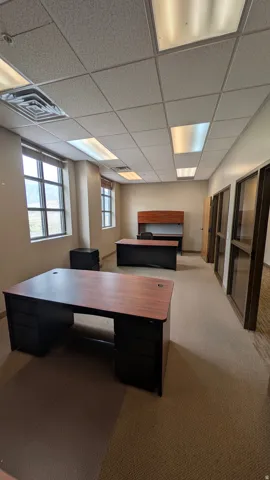 Spacious office area featuring neutral-toned carpeting and multiple windows for natural light