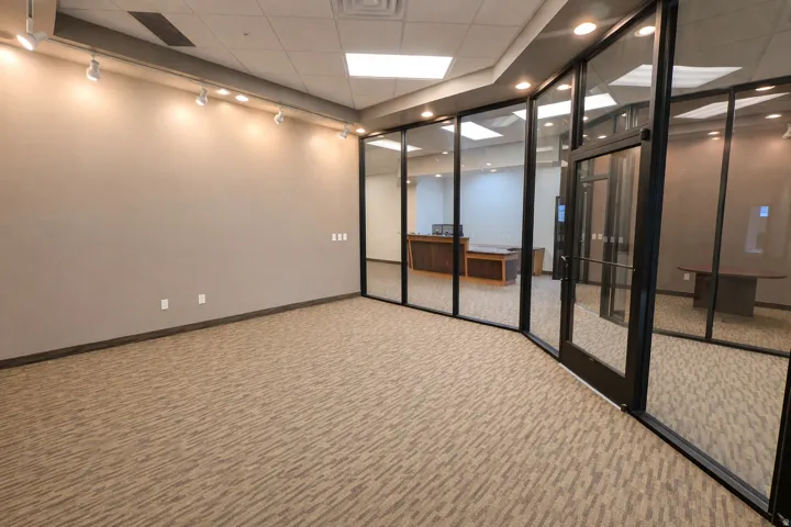 Commercial interior featuring full-height glass partitions, a suspended acoustic ceiling with recessed lighting, track lighting, and a neutral-toned carpet