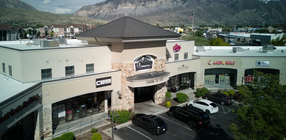 Multi-tenant commercial building featuring stone veneer accents, stucco siding, and a prominent arched entrance