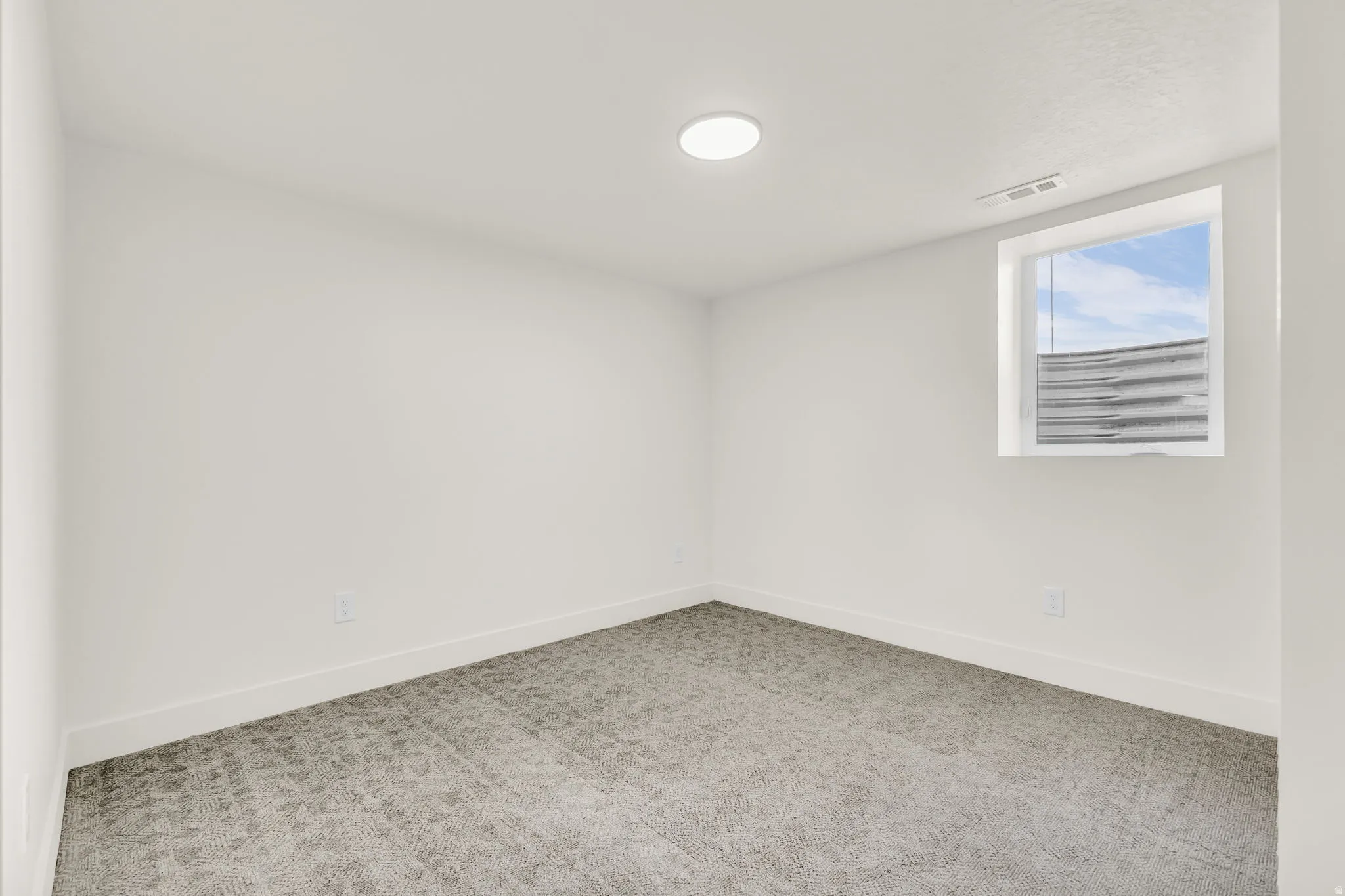 Carpeted room featuring white walls, a recessed window, a flush-mount ceiling light, and white baseboards